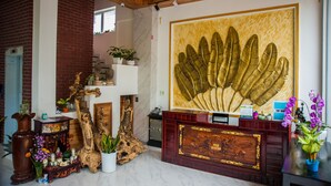 A reception area with a large golden leaf artwork, wooden furniture, and various decorative items. - Hue Four Seasons Hotel (Hue)