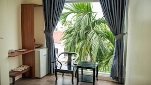A room with a small table and chair, a wooden cabinet, and a window with curtains. - Hue Four Seasons Hotel (Hue)