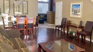 A spacious living room with a wooden coffee table, sofas, and a dining area with chairs and a table.