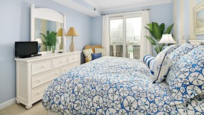 Une chambre avec un lit, une commode, une télévision et un balcon donnant sur une vue agréable.