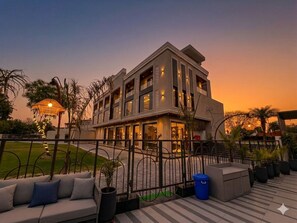 A modern hotel with a balcony, outdoor seating, and a well-lit entrance. - Hotel Palm Galaxy (Etmadpur)