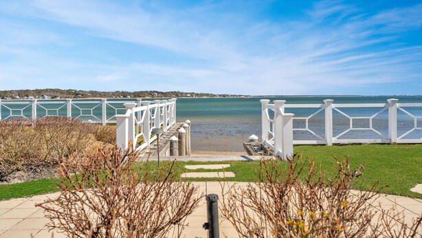 A pathway leading to a waterfront with white railings and a clear view of the water. - Hamptons Waterfront With Private Beach & Pool (Hampton Bays)