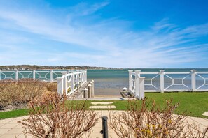 A pathway leading to a waterfront with white railings and a clear view of the water.