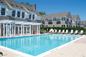 Ein Schwimmbecken mit Liegestühlen und einer überdachten Terrasse.