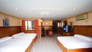 Habitación de hotel con dos camas, un escritorio, una silla, un televisor y aire acondicionado.
