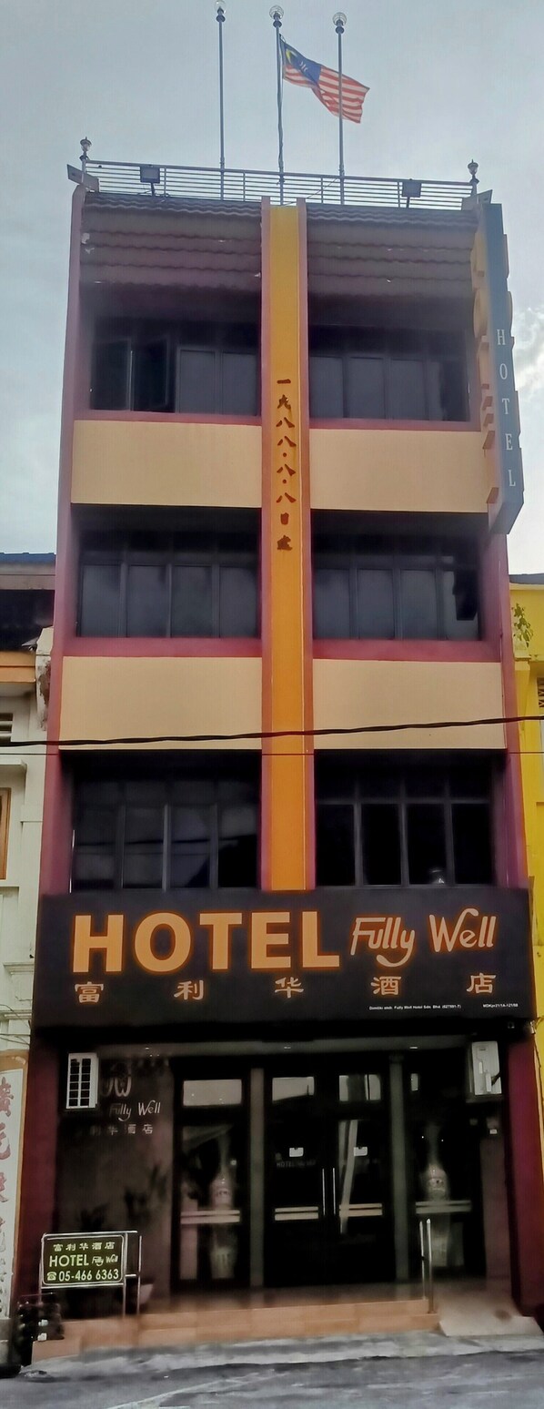 Un hotel con un cartel grande que dice "HOTEL Fully Well", varios pisos y una bandera estadounidense en la parte superior.