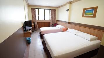 Een hotelkamer met twee bedden, een bureau, een stoel, een televisie en een raam met gordijnen.