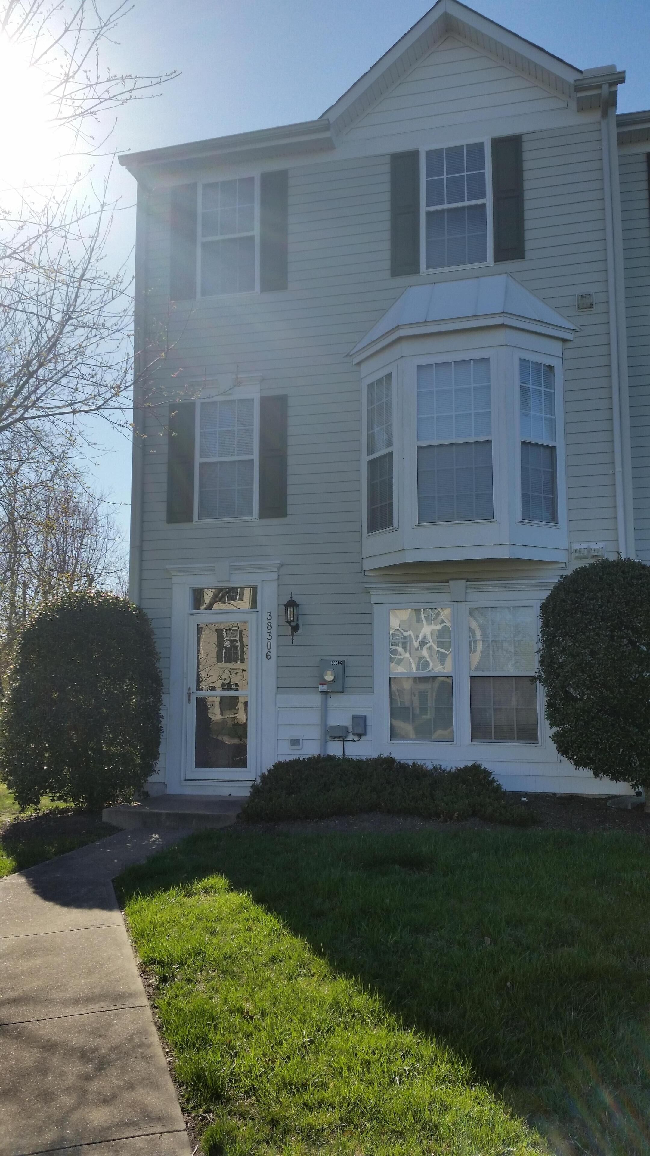 A two-story house with a bay window, a front door, and a mailbox.