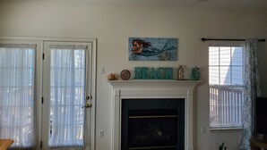 Un salon avec une cheminée, un tableau représentant une sirène et le mot « PLAGE » écrit sur le manteau de la cheminée.