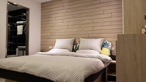 Un dormitorio moderno con cabecera de madera, cama con ropa de cama a rayas y mesita de noche con almohada de piña.