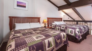 Twee bedden met houten hoofdborden, een nachtkastje met een lamp en een lijst met een afbeelding aan de muur.