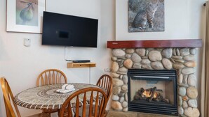 Een gezellig eetgedeelte met een stenen openhaard, een flatscreen televisie aan de muur en een kunstwerk erboven.