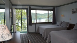 Une chambre d’hôtel avec deux lits, une vue sur le lac, une lampe et une chaise.