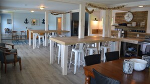 Une cuisine spacieuse avec un îlot central en bois, des tabourets de bar blancs et une grande horloge au mur.