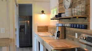 Une cuisine moderne dotée d’appareils électroménagers en acier inoxydable, d’étagères en bois et d’une horloge intégrée.