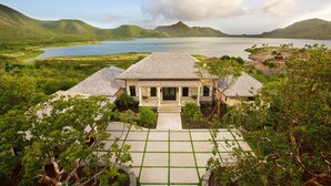 A house with a porch, a view of a lake, and surrounding greenery. - Beautiful 4 bedroom Caribbean Villa (Basseterre)