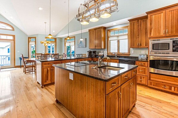 Enjoy cooking in this well-equipped kitchen with a large island, stainless steel sink, and modern faucet.
