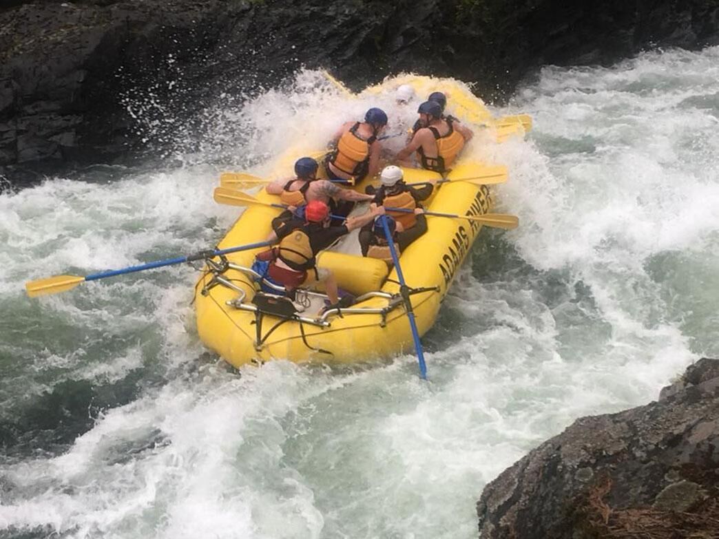 Un grupo de personas en un bote amarillo navegando por un río con rápidos.