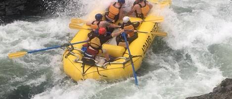 Un grupo de personas en un bote amarillo navegando por un río con rápidos.