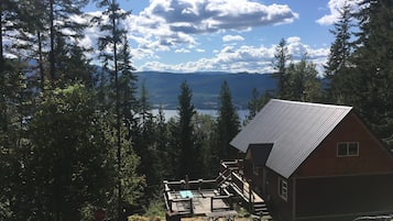 Situated in a forested area, this cabin offers a serene view of a lake and distant mountains.