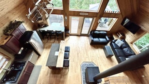 Interior acogedor de una cabaña con comedor, asientos y chimenea.