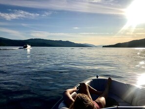 A person lying on a boat in a calm lake with mountains in the background. - Cozy Cariboo Cabin w/ HOT TUB - Shuswap Vacations and Sledding Accommodation (Anglemont)