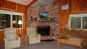 Una sala de estar acogedora con chimenea de ladrillo, muebles de madera y un televisor montado sobre ella.
