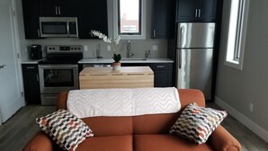 Eine moderne Küche mit dunklen Schränken, Edelstahlgeräten und einem Holztisch.