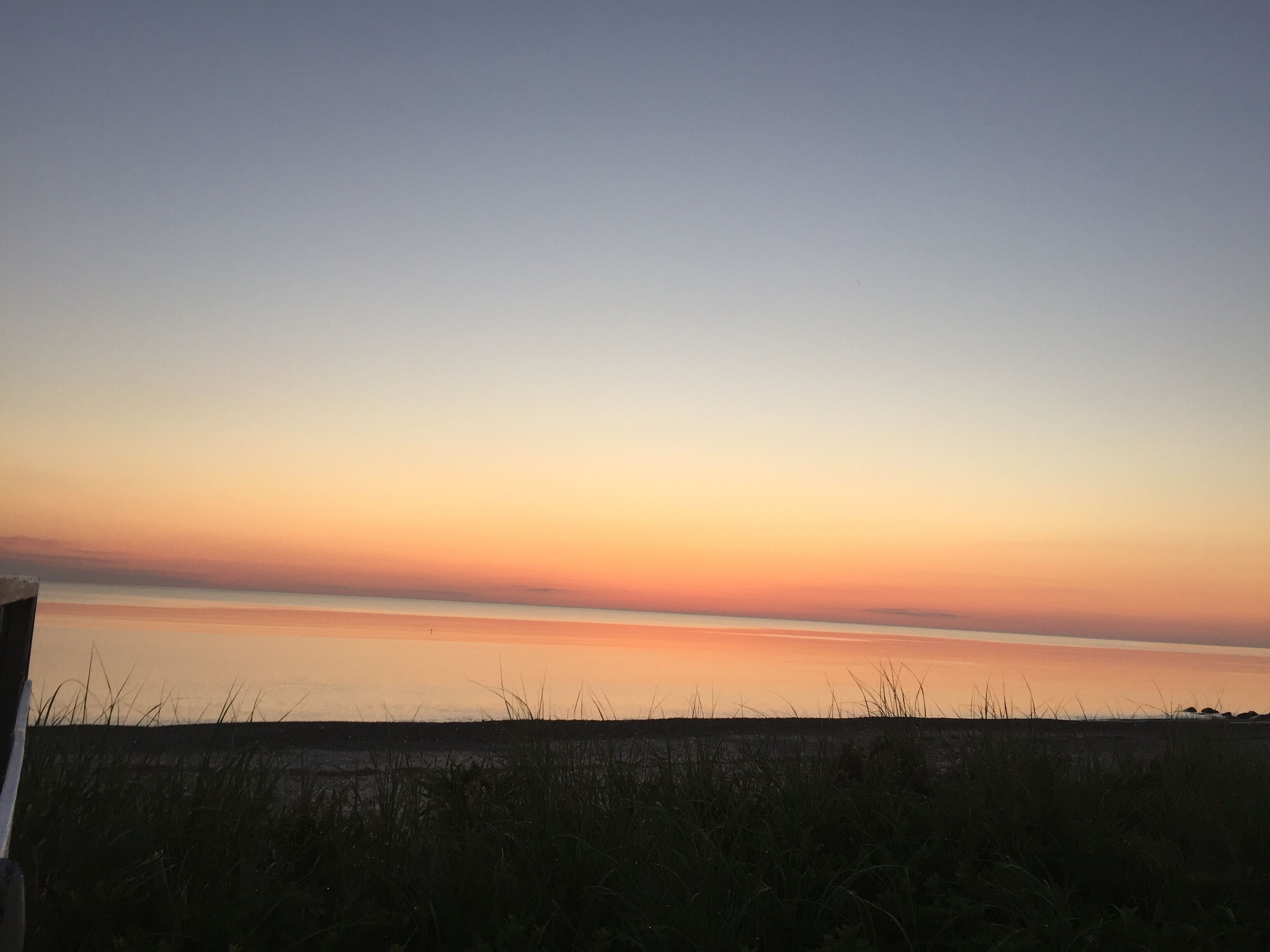 Solnedgang over et fladt landskab med en klar horisont.
