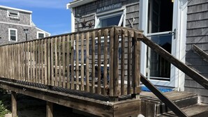 A wooden deck leading to a beach cottage with a white exterior and a window with a view of the beach. -  Cozy Cape Cottage on Private Beach with HVAC split AC/Heating system (Sandwich)