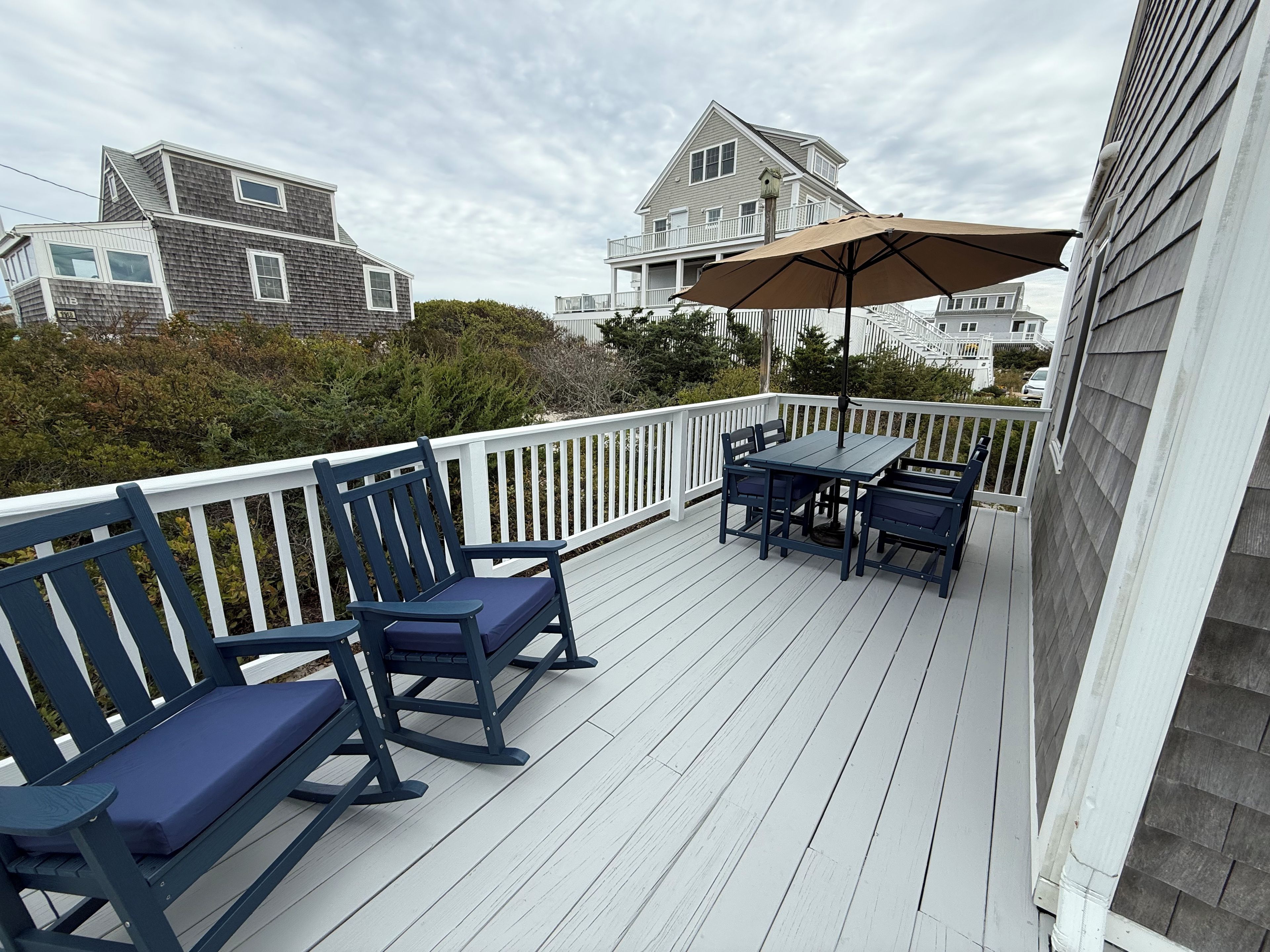 A wooden deck with a table and chairs, a bench, and a large umbrella.