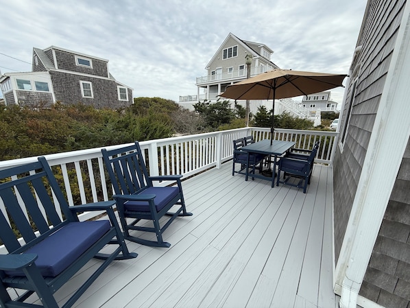 A wooden deck with a table and chairs, a bench, and a large umbrella. -  Cozy Cape Cottage on Private Beach with HVAC split AC/Heating system (Sandwich)