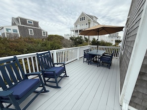 A wooden deck with a table and chairs, a bench, and a large umbrella. - Cozy Cape Cottage on Private Beach with HVAC split AC/Heating system (Sandwich)