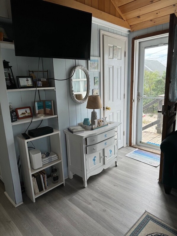 Una habitación con un aparador blanco, un televisor montado encima y una puerta que da al exterior.