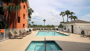 A pool area with lounge chairs and a building with a red facade.