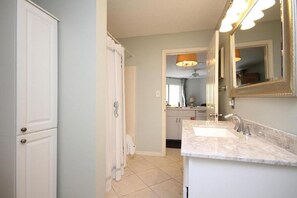 A bathroom with a double sink, a large mirror, and a shower area. - Beautiful Ground Floor Unit! (Miramar Beach)