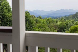 A view from a balcony with a railing, overlooking a forested landscape and distant mountains. - Mountain View ranch w/ sauna, 1ac fence & firepit. (Candler)