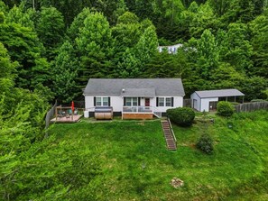 A residential property with a house, a small shed, a wooden deck, and a well-maintained lawn. - Mountain View ranch w/ sauna, 1ac fence & firepit. (Candler)