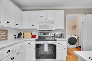 A compact kitchen with white cabinets, a microwave, a toaster, and a washing machine. - Mountain View ranch w/ sauna, 1ac fence & firepit. (Candler)