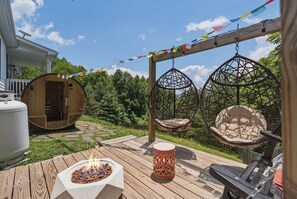 A wooden deck with a fire pit, two hanging chairs, and a wooden structure with a door. - Mountain View ranch w/ sauna, 1ac fence & firepit. (Candler)
