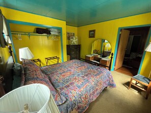 Una habitación con una cama, un tocador, un espejo y una silla.
