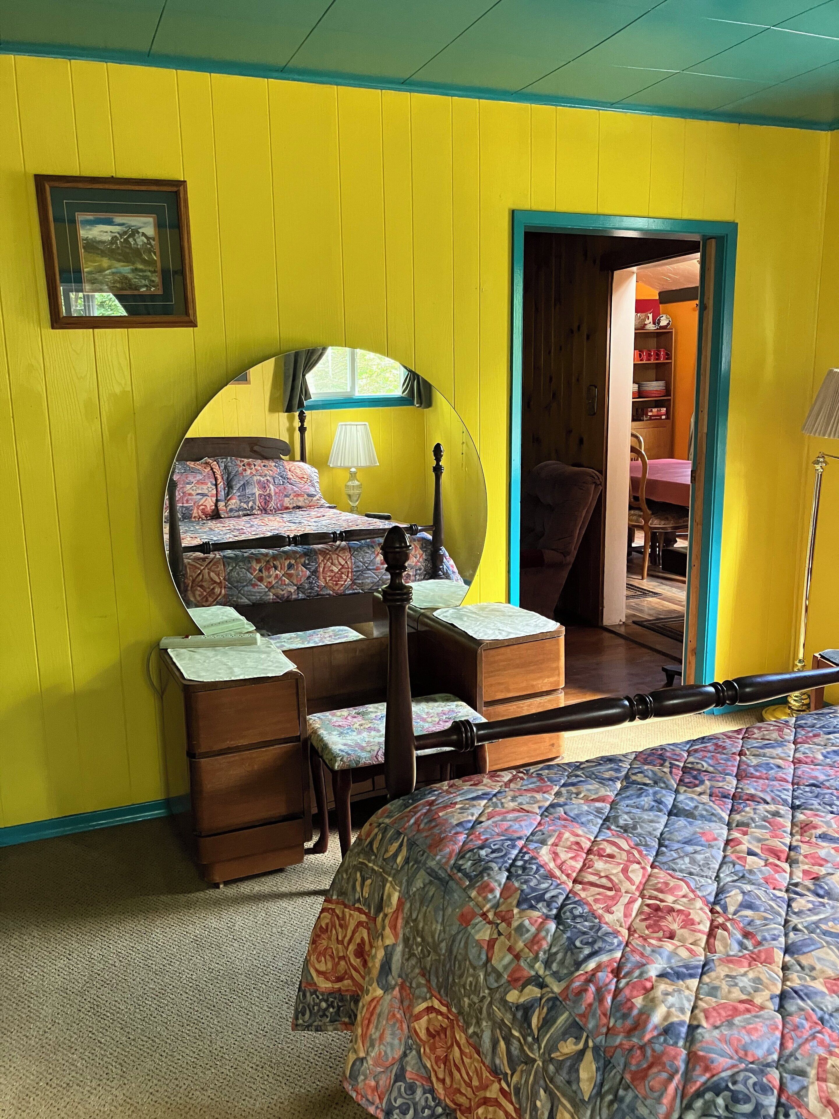 Une chambre à coucher avec un lit, une commode, un miroir et une fenêtre.