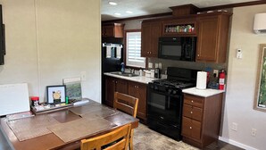 Une cuisine avec des meubles de rangement en bois, une cuisinière noire, un four à micro-ondes et un évier.