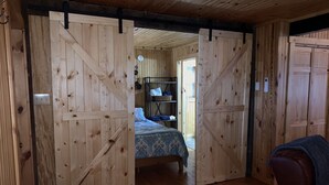A room with a bed, wooden walls, and a sliding barn door.