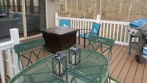 A deck with outdoor furniture, a grill, and string lights.