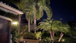 Una propiedad residencial con garaje, jardín bien cuidado y altas palmeras.