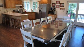 A spacious kitchen with wooden cabinets, a stainless steel refrigerator, a microwave, and a dining table with white chairs.