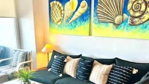 Una sala de estar con sofá, mesa de centro y una obra de arte en la pared.