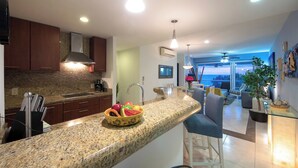 Una cocina moderna con encimeras de granito, un frutero y un comedor con vistas.