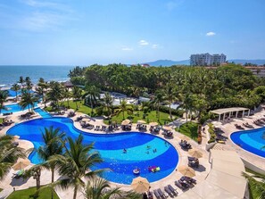 Et resort med flere swimmingpools, palmer og havudsigt.
